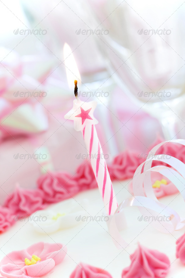 Pink and white birthday cake decorated with a single candle
