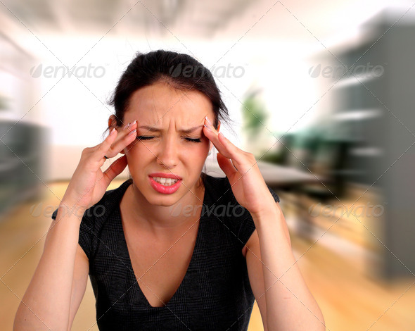 Portrait of a woman heaving a headache at work