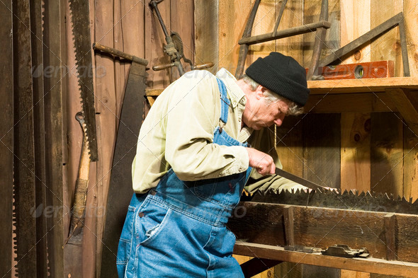 man sharpening an old loggers saw in his workshed