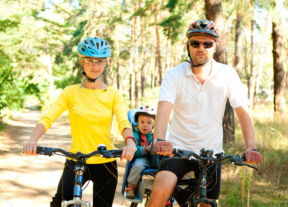 Father, mother and son on the bikes in the sunny forest