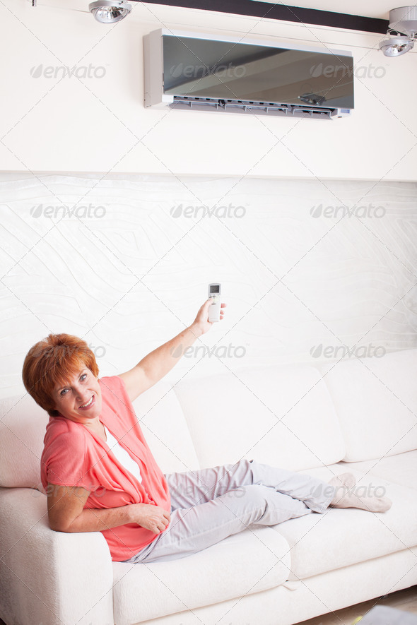 Woman holding a remote control air conditioner