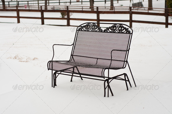 Metal bench with snow in a backyard