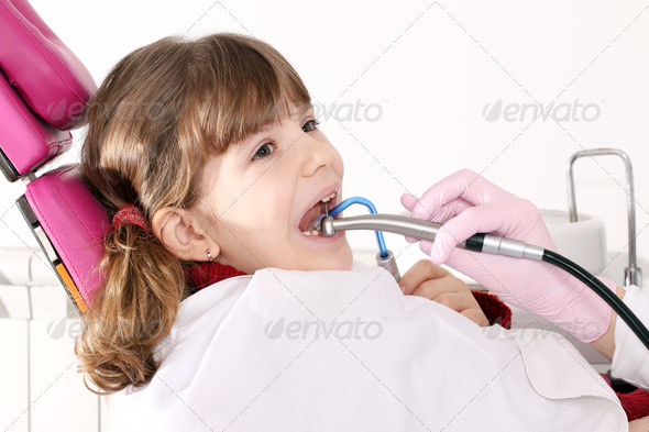 little girl with open mouth during drilling treatment at the dentist