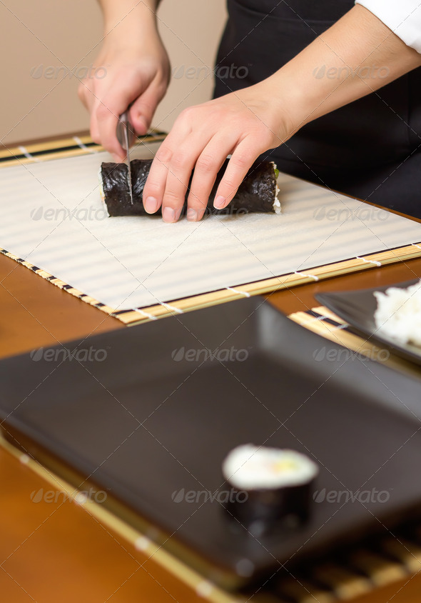 Closeup of woman chef cutting japanese sushi roll