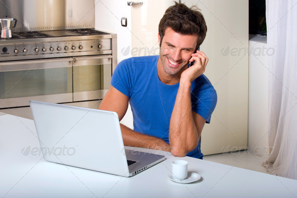 man in the kitchen with laptop and mobile